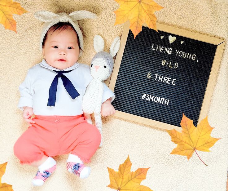 a baby is laying on a blanket with a stuffed animal and a sign that says living young, wild