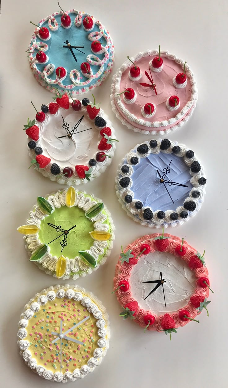 four different clocks made out of plastic plates and strawberries on the top one is decorated with cherries