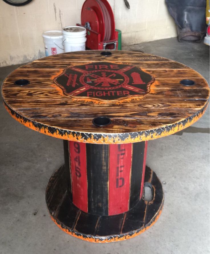 a table made out of an old barrel with fire fighters painted on the top and bottom