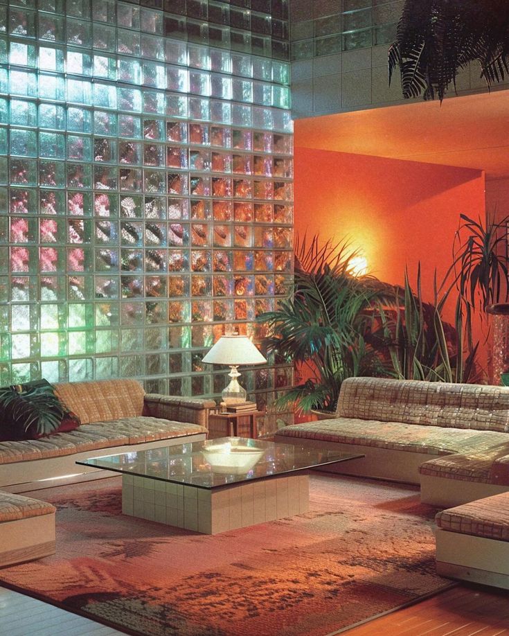 a living room filled with lots of furniture next to a wall covered in glass blocks