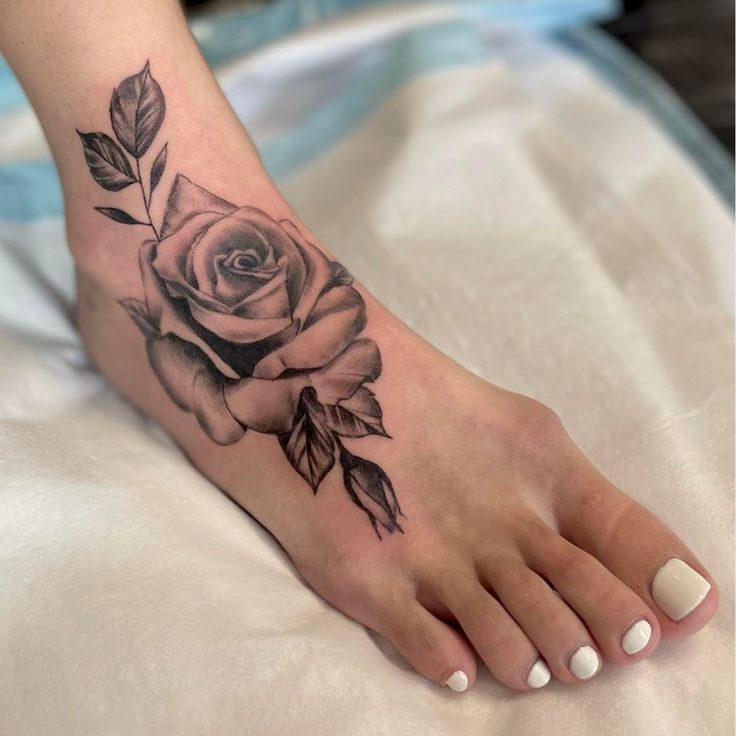 a woman's foot with a rose tattoo on it