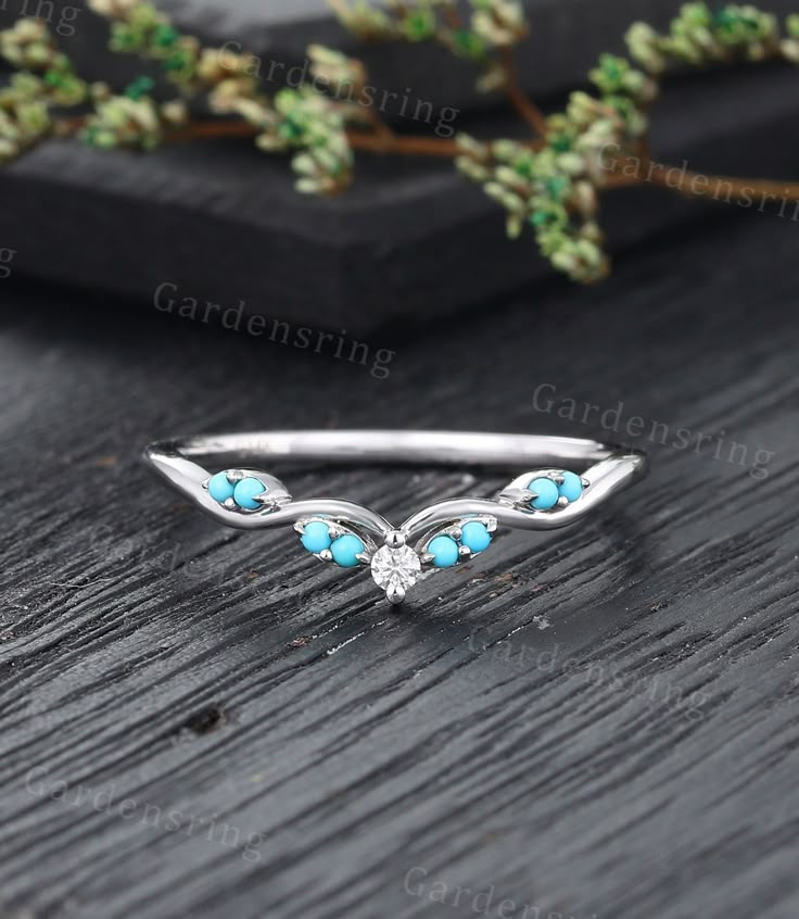 an image of a ring with turquoise stones on it and leaves in the back ground