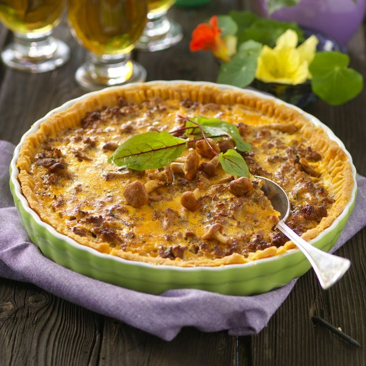 a pie sitting on top of a wooden table next to two glasses filled with beer