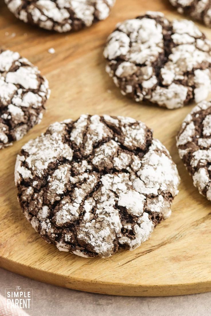 chocolate crinkle cookies on a wooden cutting board with powdered sugar over them