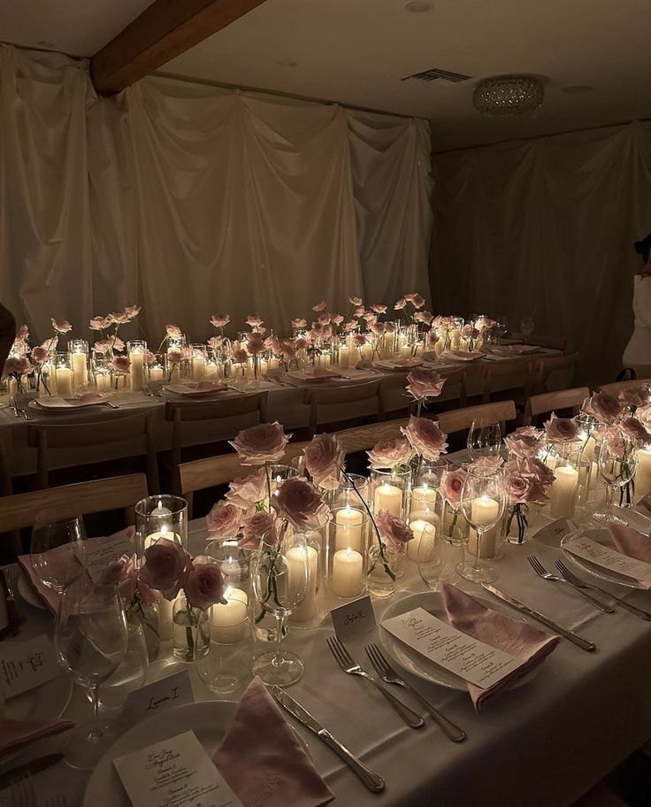 a long table is set with candles and flowers in glass vases on the tables