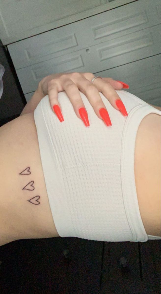 a woman with red nail polishes on her stomach and arm, showing the word va written in cursive writing