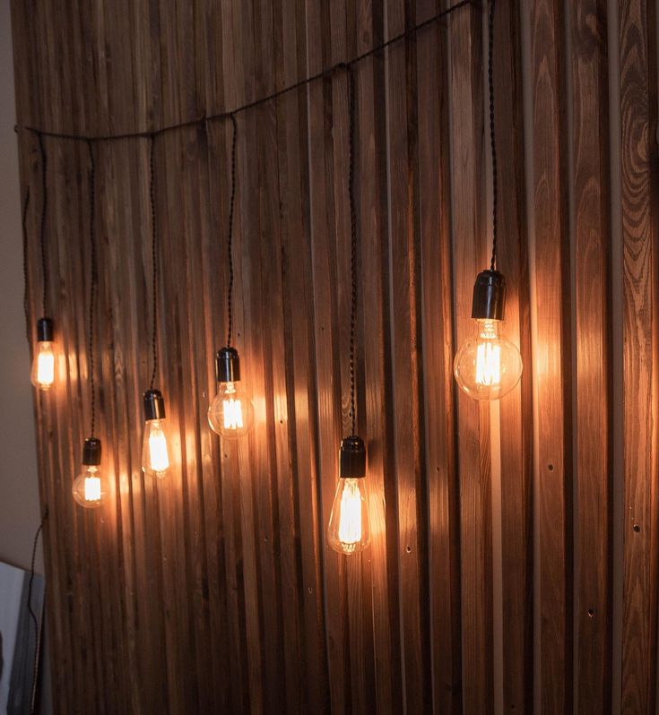 some light bulbs are hanging on a wooden wall