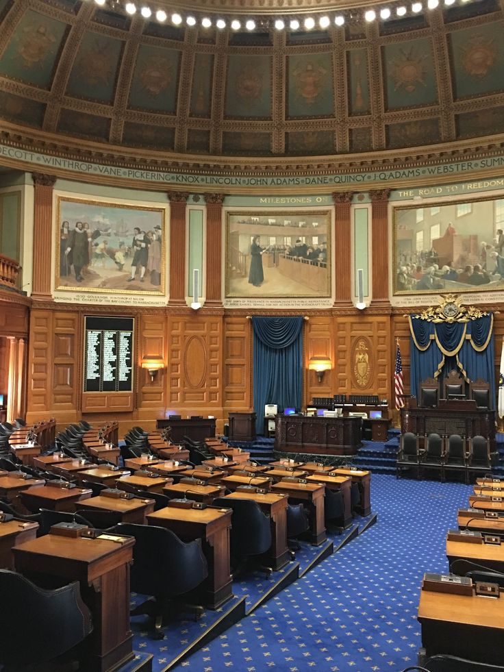 an empty room with blue carpet and wooden desks