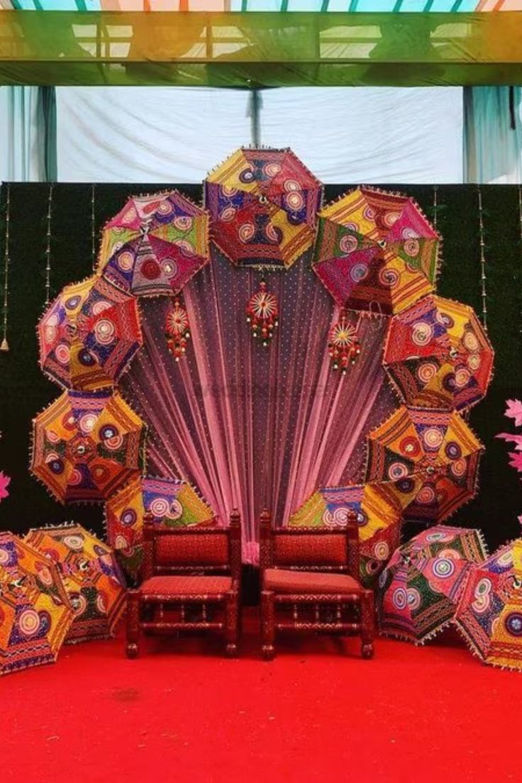 an elaborately decorated stage with chairs and umbrellas on the red carpeted floor