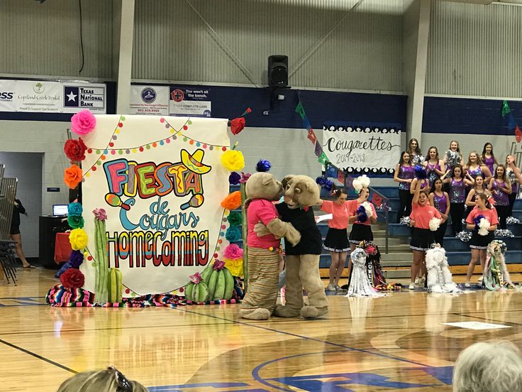 some people are standing on a basketball court while others stand in front of a sign