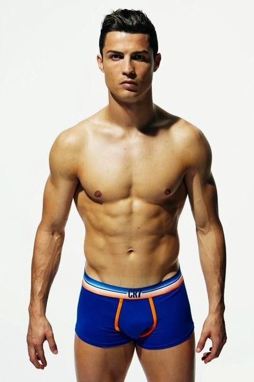 a shirtless man in blue and orange trunks posing for the camera with his hands on his hips