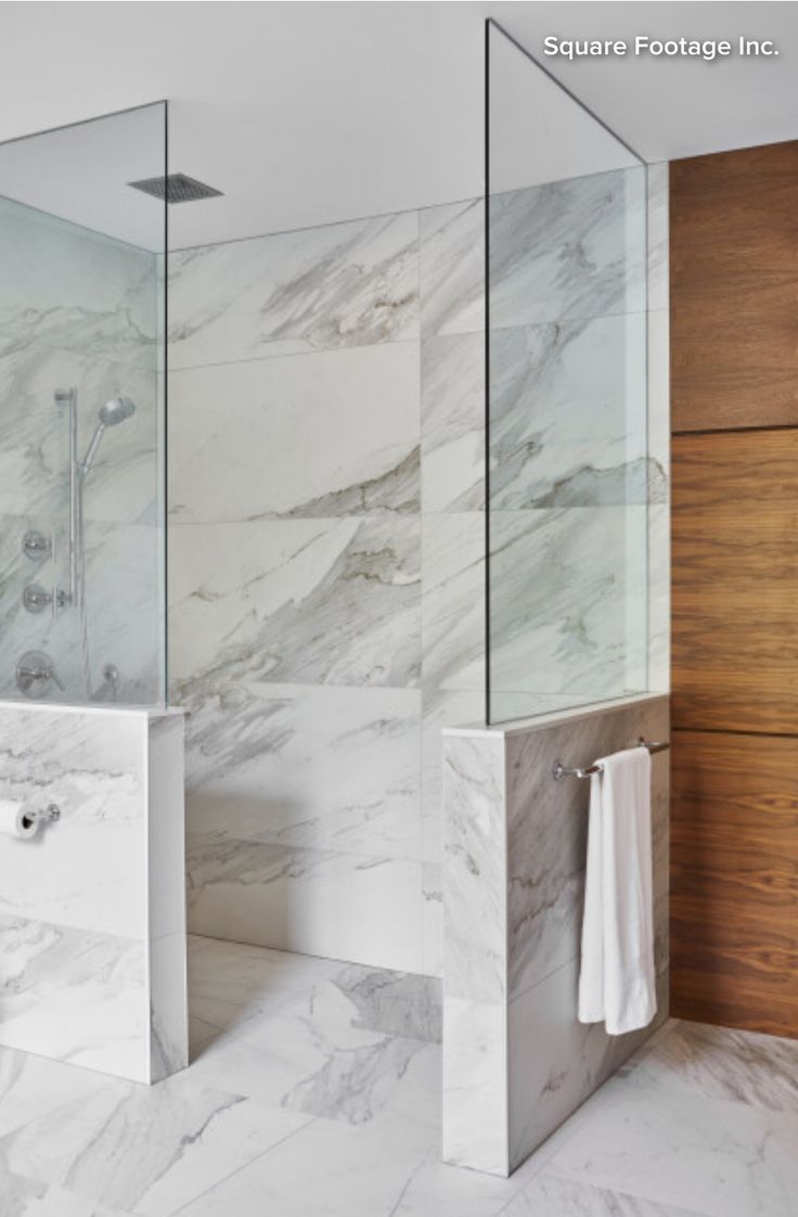 a bathroom with marble walls and flooring next to a walk - in shower stall