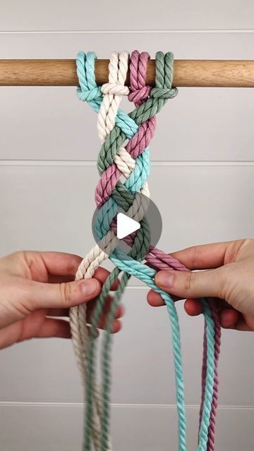 two hands are holding different colored ropes with one hand and the other is pulling them together