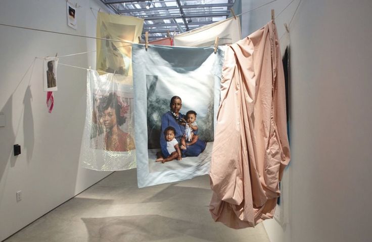 an art exhibit with clothes hanging from the ceiling