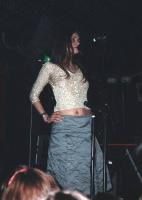 a woman standing in front of a microphone with her hands on her hips while wearing a skirt