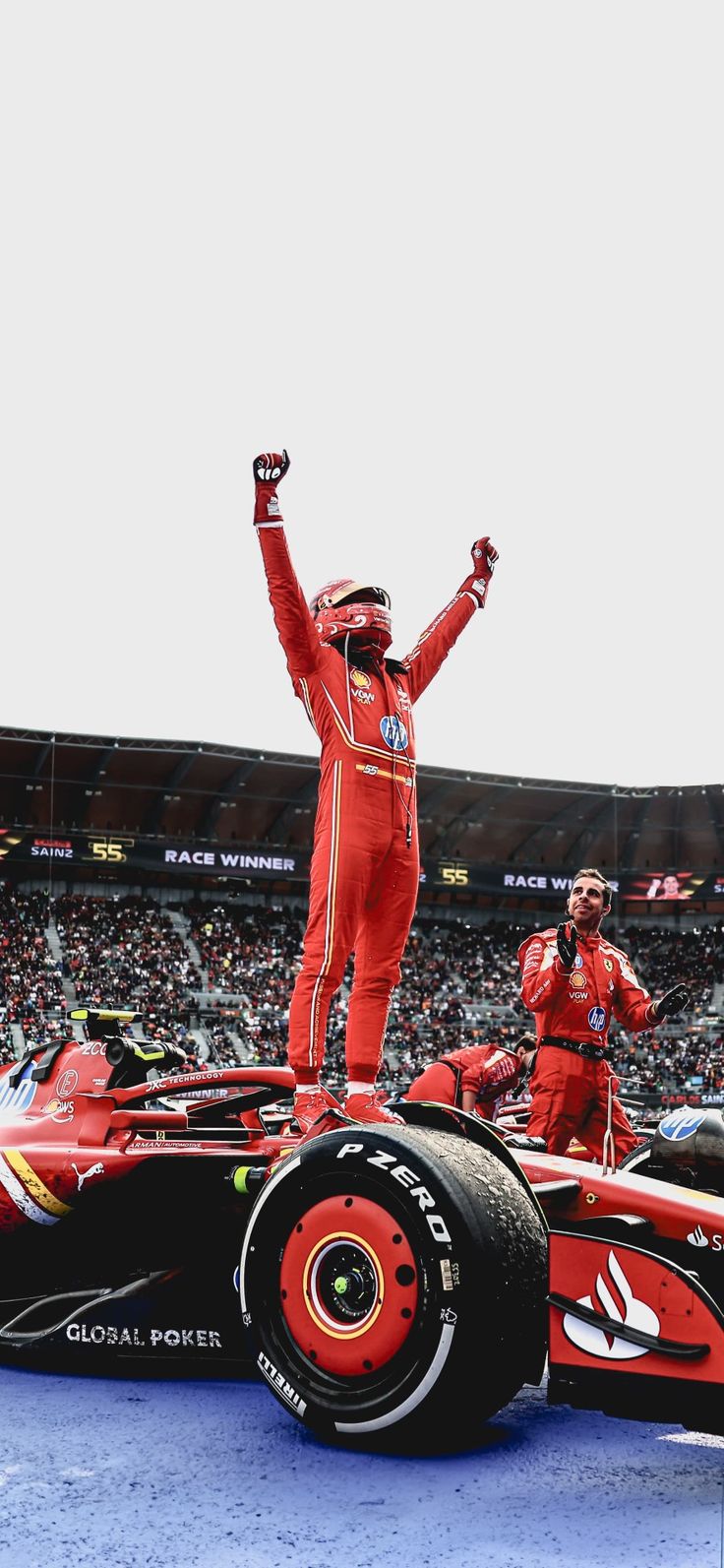 a man standing on top of a red race car in front of a large crowd