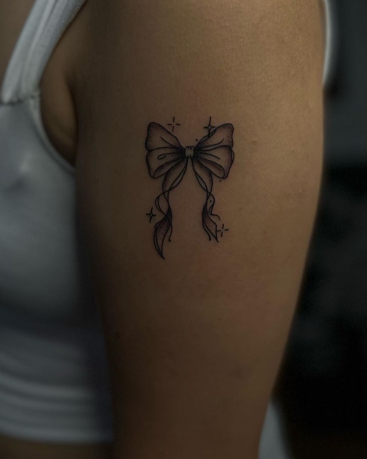 a woman's thigh with a bow tattoo on her left side ribcage