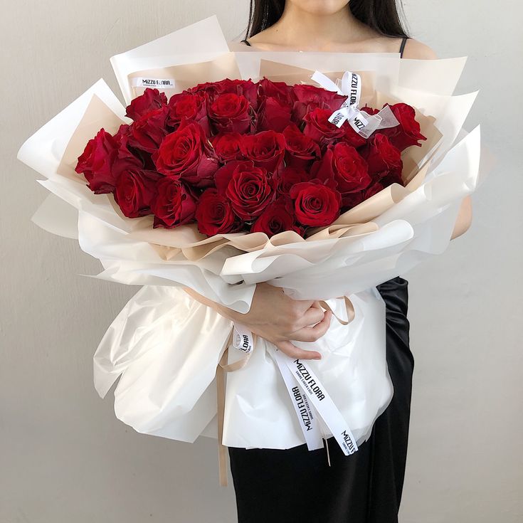 a woman holding a large bouquet of red roses in her hands with the words written on them