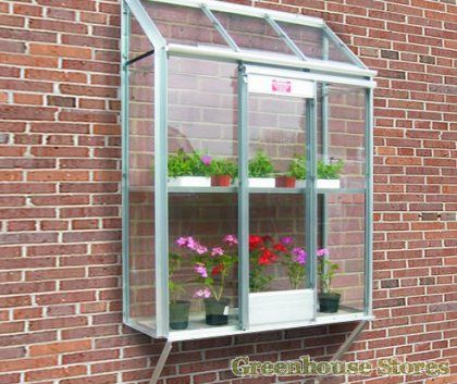 several potted plants are sitting in a window sill on the side of a brick building