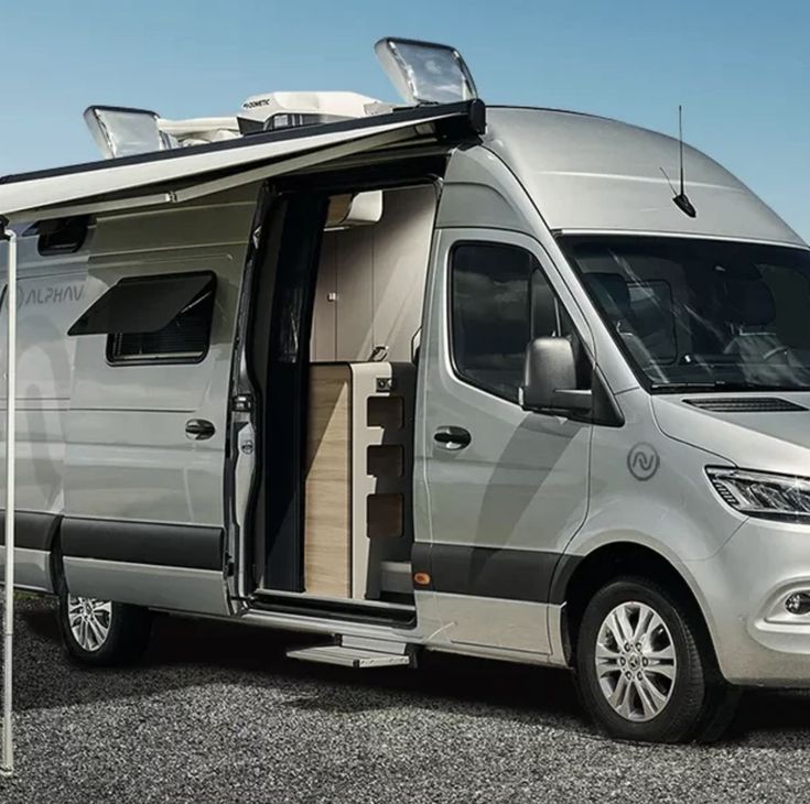 an rv parked in a parking lot with its door open and the roof opened up