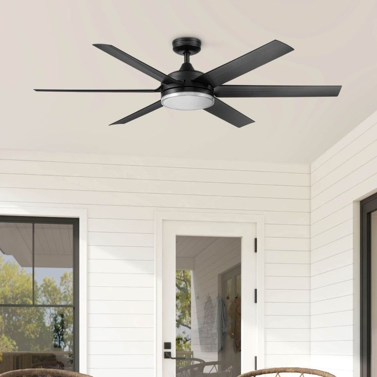 a ceiling fan that is on the outside of a house with two chairs and a table