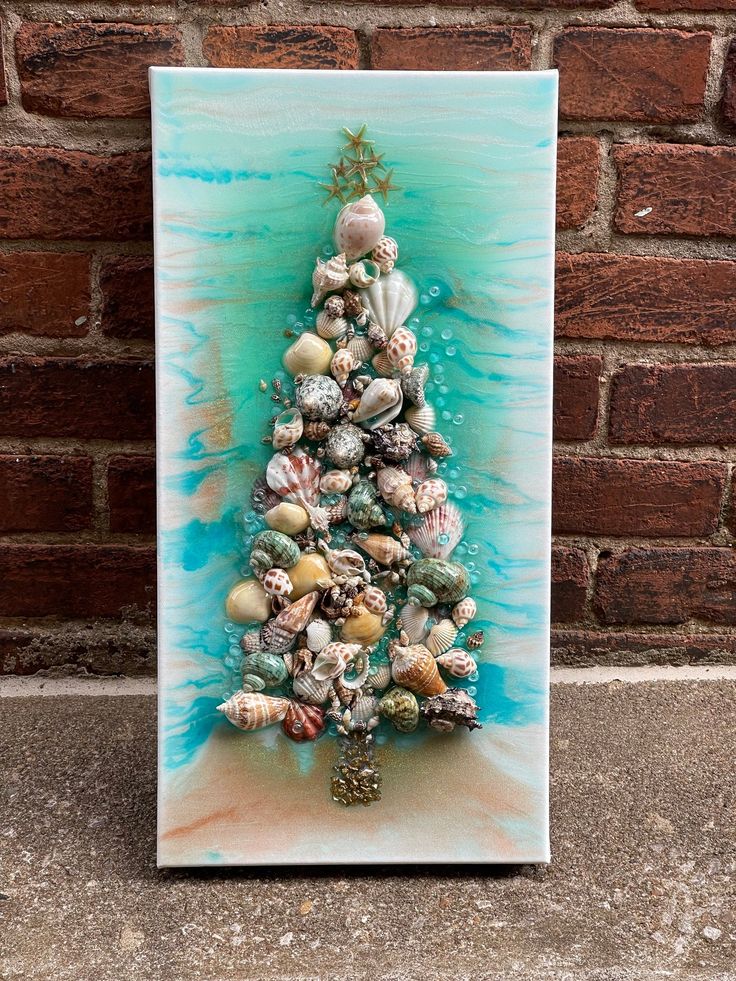 a small christmas tree made out of seashells on a blue and white background