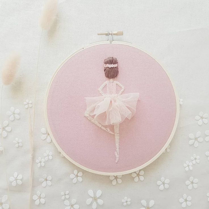 a ballerina doll sitting on top of a white table next to a pink hoop