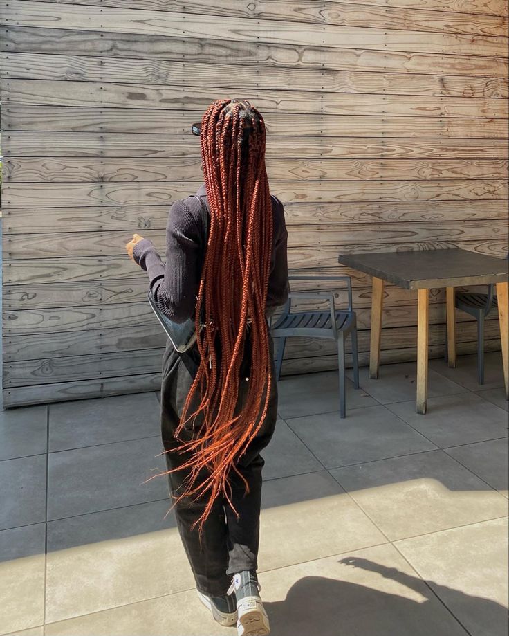 a woman with long red braids walking down the street in front of a building