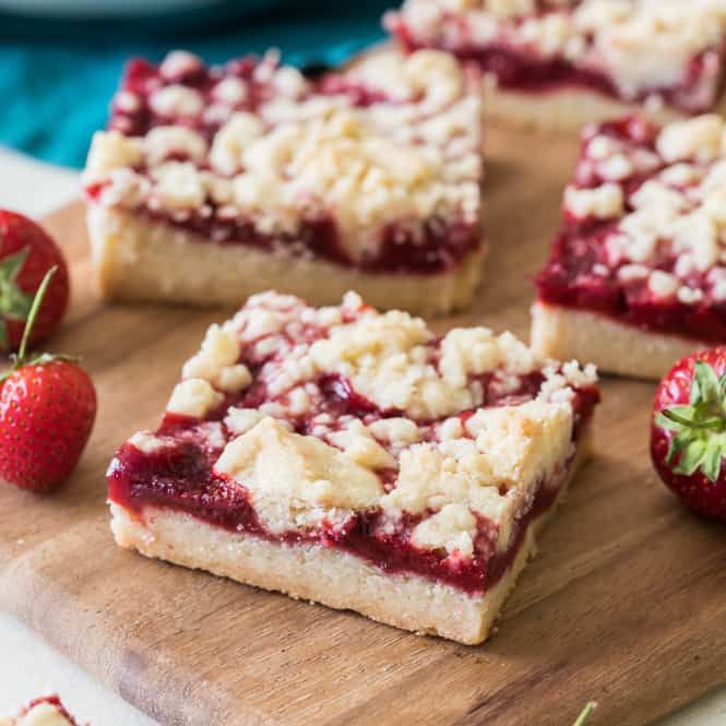 strawberry crumb bars on a cutting board with strawberries in the background and text overlay