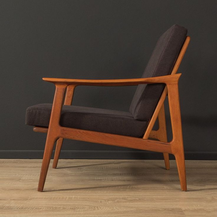 a wooden chair sitting on top of a hard wood floor next to a black wall