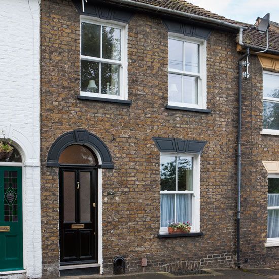 a brick building with white windows and green door