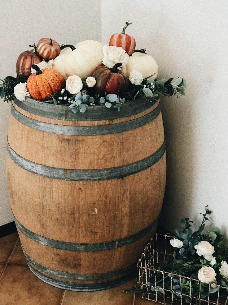 a wooden barrel filled with pumpkins and flowers