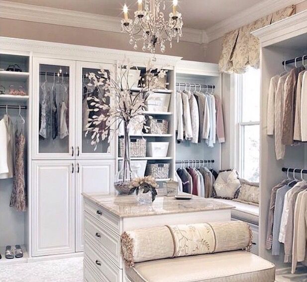 a walk in closet filled with lots of clothes and drawers next to a chandelier