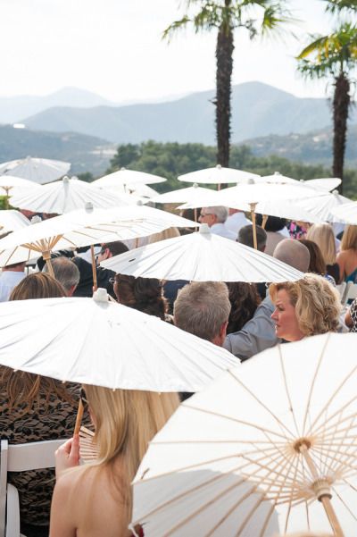 many people are sitting under umbrellas at an outdoor event