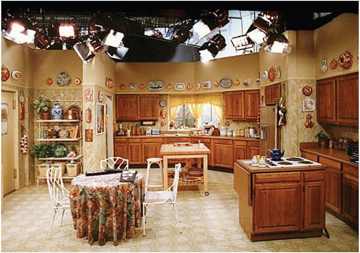 a kitchen with lots of wooden cabinets and lights hanging from the ceiling over the stove top