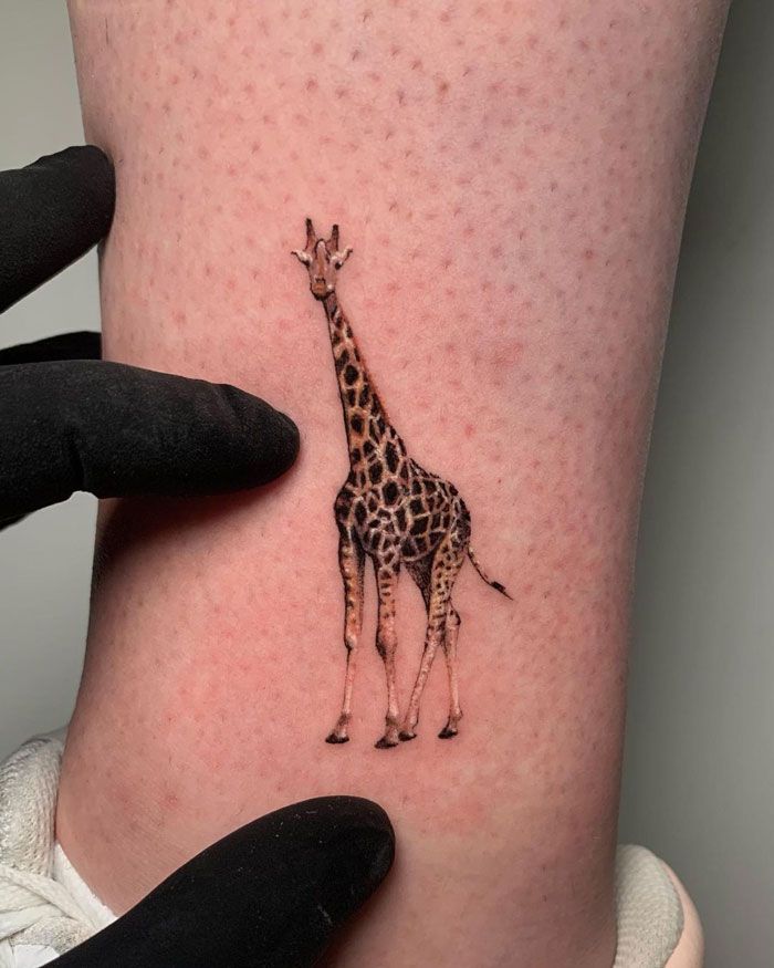 a small giraffe tattoo on the leg of a woman