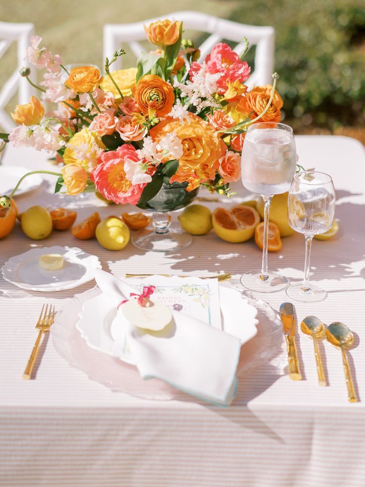 the table is set with orange and pink flowers