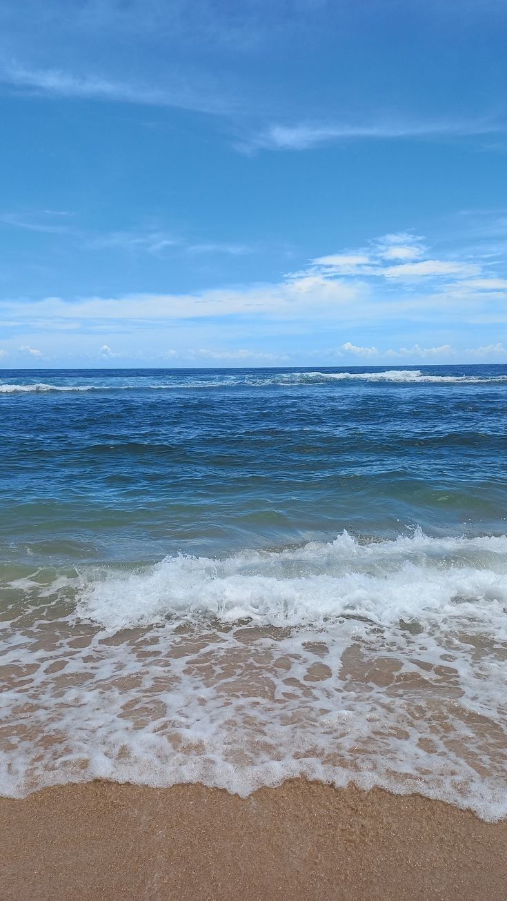 the ocean waves are rolling in and out of the water on a sunny day with blue skies