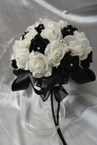 a bridal bouquet with white roses and black ribbons on a satin fabric draped background