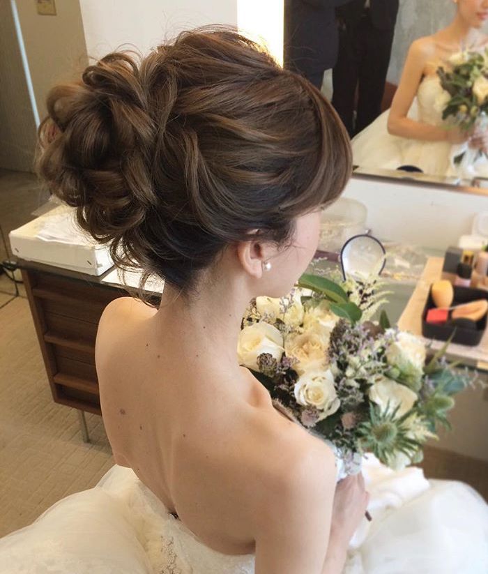 a woman in a wedding dress is looking at herself in the mirror and holding a bouquet