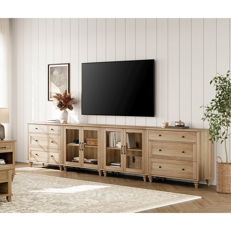 a large flat screen tv mounted to the side of a wooden entertainment center in a living room