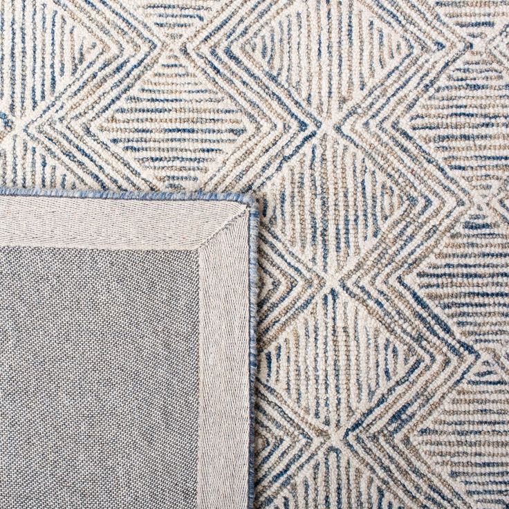 a blue and white rug next to a wall with an area rug on top of it