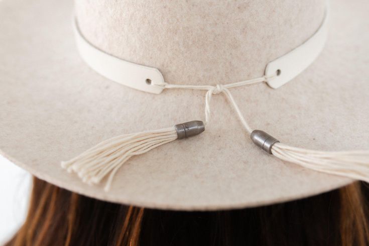 We love this white leather hat band! This hat band features a tie back with tassels trimmed with metal GP engraved caps. This hat band is made of genuine leather. Simply place this leather band around the crown of your hat + tie the strings into a knot to keep in place. Let the tassels hang down. Chic Adjustable White Hat Band, Classic White Hat Band, Classic White Hat Band For Rodeo, White Bohemian Hat Bands, Classic White Rigid Hat Bands, Gigi Pip, Fedora Hat Women, Hat Bands, Bead Loom Designs