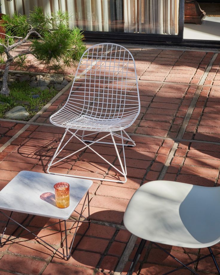 two chairs sitting on top of a brick patio next to a table with a drink in it