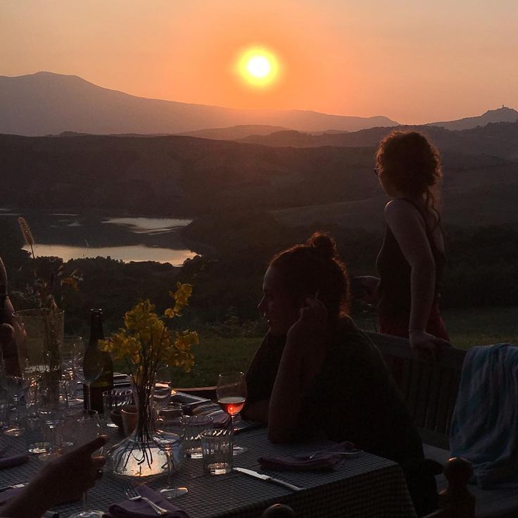 several people sitting at a table with wine glasses in front of the sun