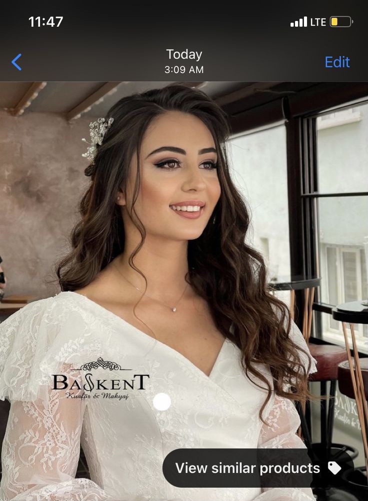 a woman wearing a white wedding dress with long sleeves and a flower in her hair