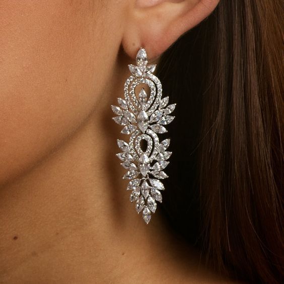 a close up of a woman's face wearing large earrings with crystal stones on them