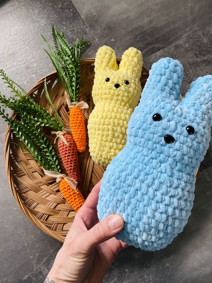 two crocheted stuffed animals sitting next to each other in front of a basket