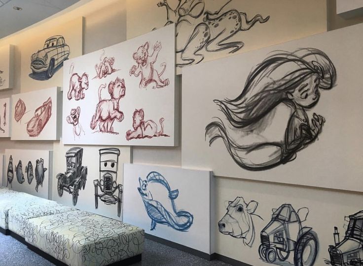 a room with several drawings on the wall and two benches in front of one another