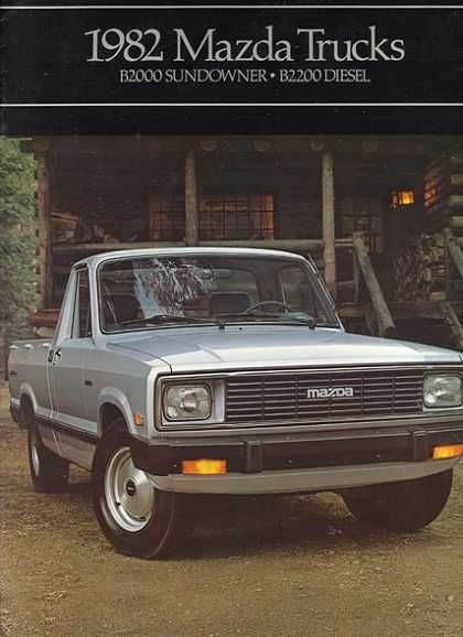 an old pickup truck parked in front of a log cabin with the words mazda trucks written on it